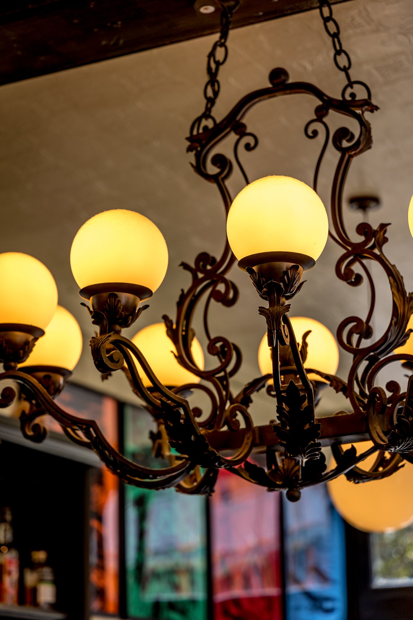 A vintage chandelier with multiple warm-colored globe lights and ornate metal details hanging from a chain.