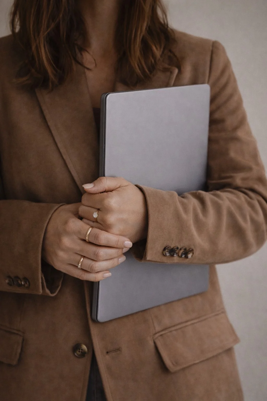 Designcoach Angela Lund i en brun jakke, som holder en laptop.