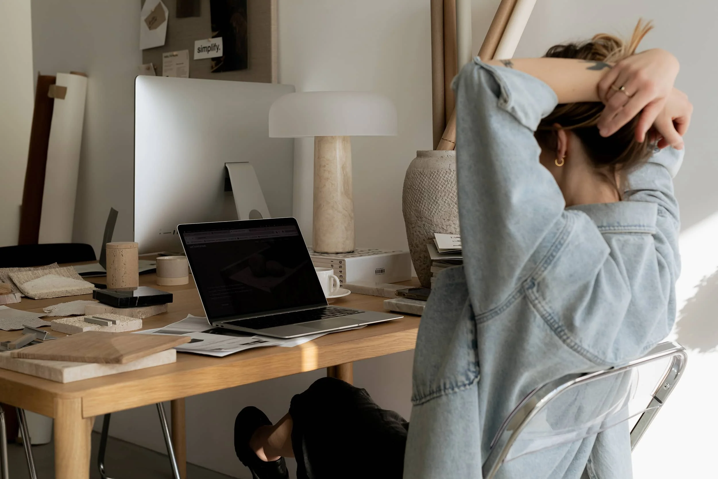 Designer i sit designsudio siddende ved arbejdsbord med laptop