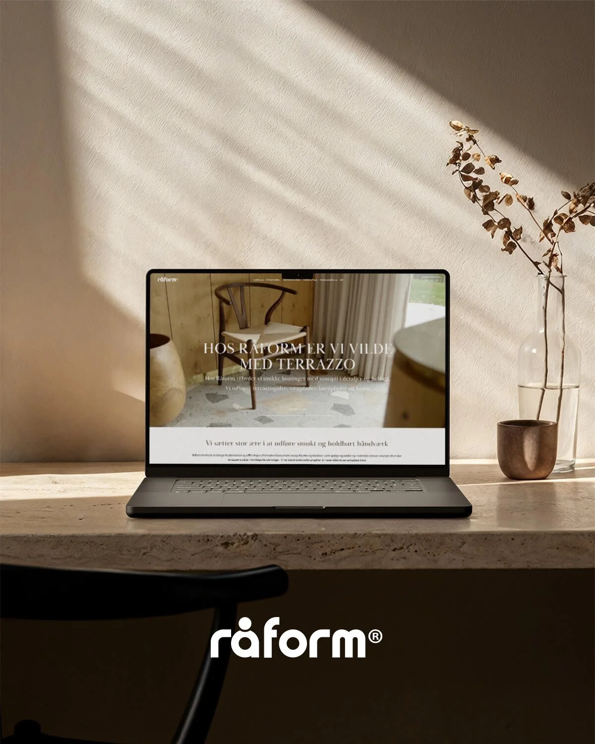 Laptop på bord med hjemmeside designet for Råform, om terrazzo, i et rum med sollys, planter og bord.