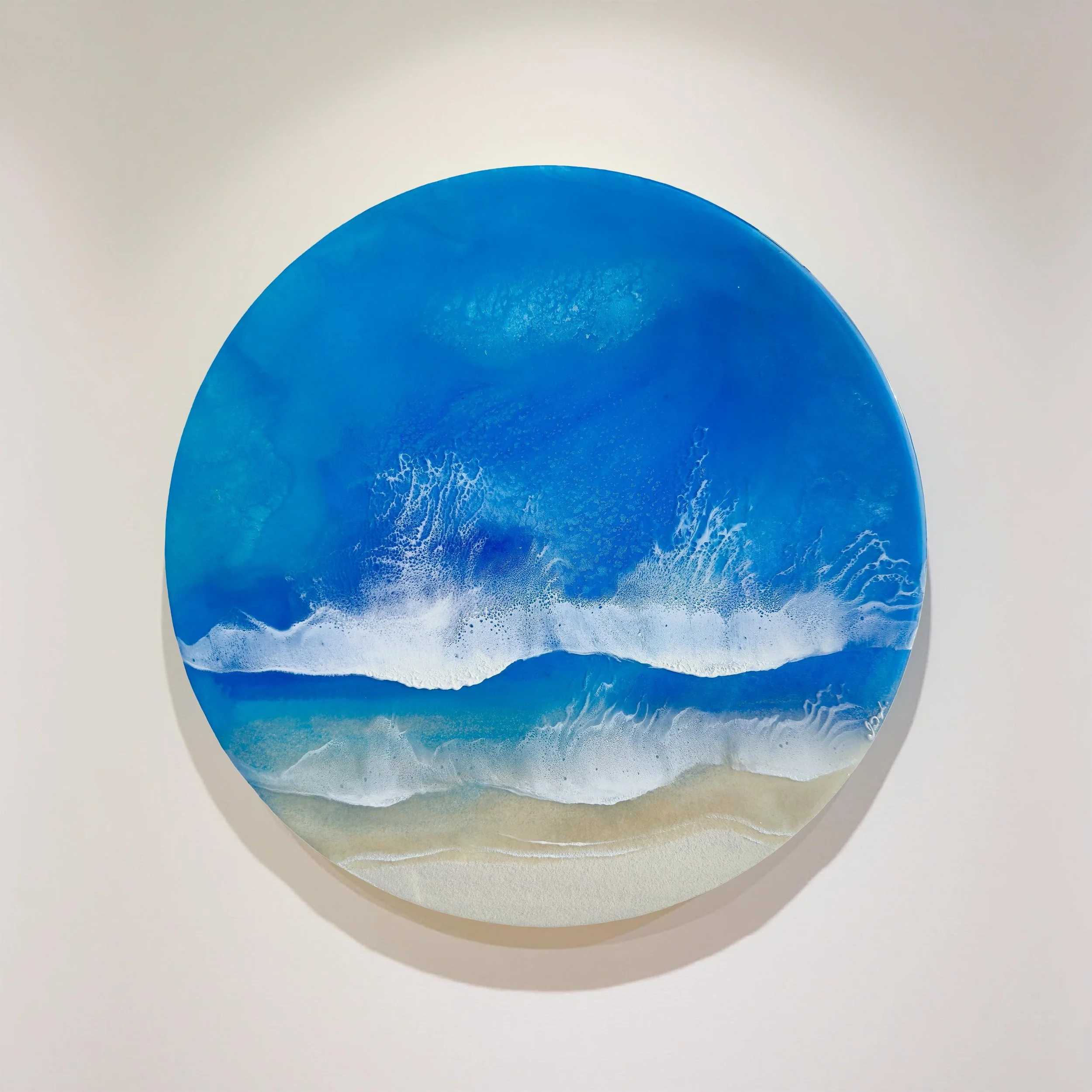 Round resin artwork featuring turquoise ocean water, two white foam wave bands, and sandy shoreline in realistic detail.