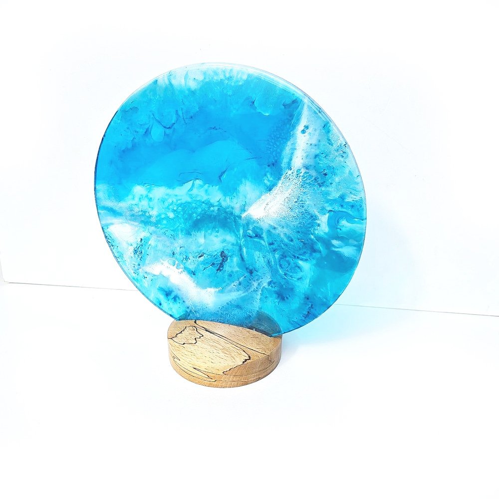 Round blue resin artwork on a wooden base with abstract swirling patterns.