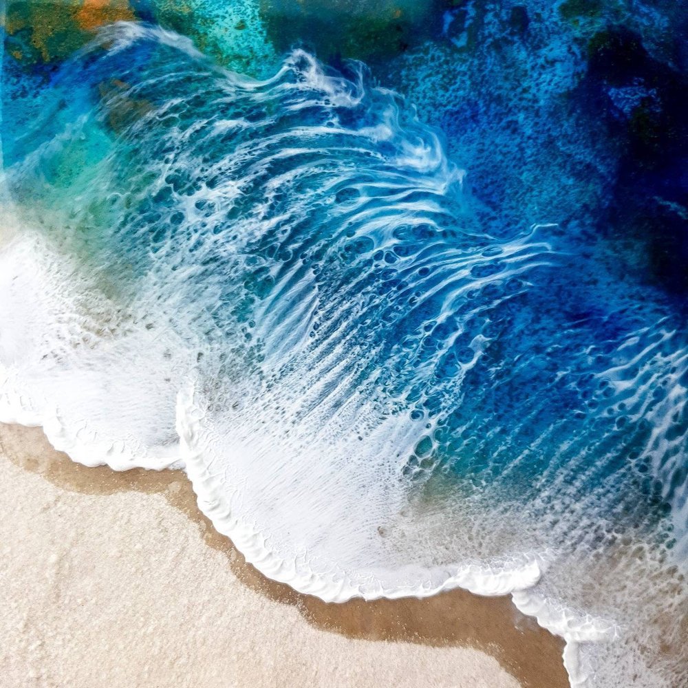 Close up of ocean-inspired resin painting with black sand and indigo tones capturing realistic beach beauty.
