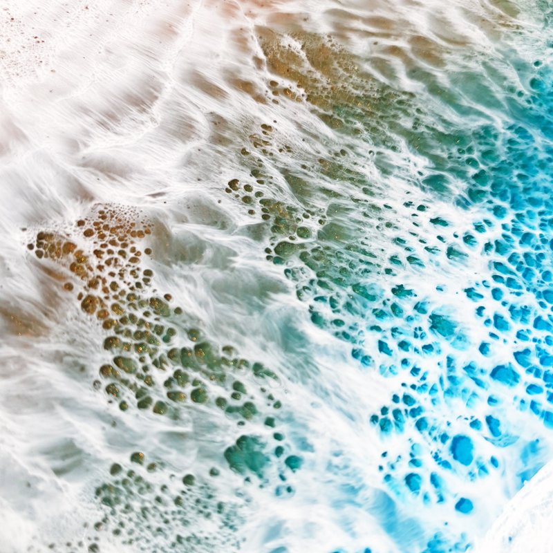 Close up of ocean-inspired resin painting with turquoise and emerald tones, capturing abstract beach beauty.