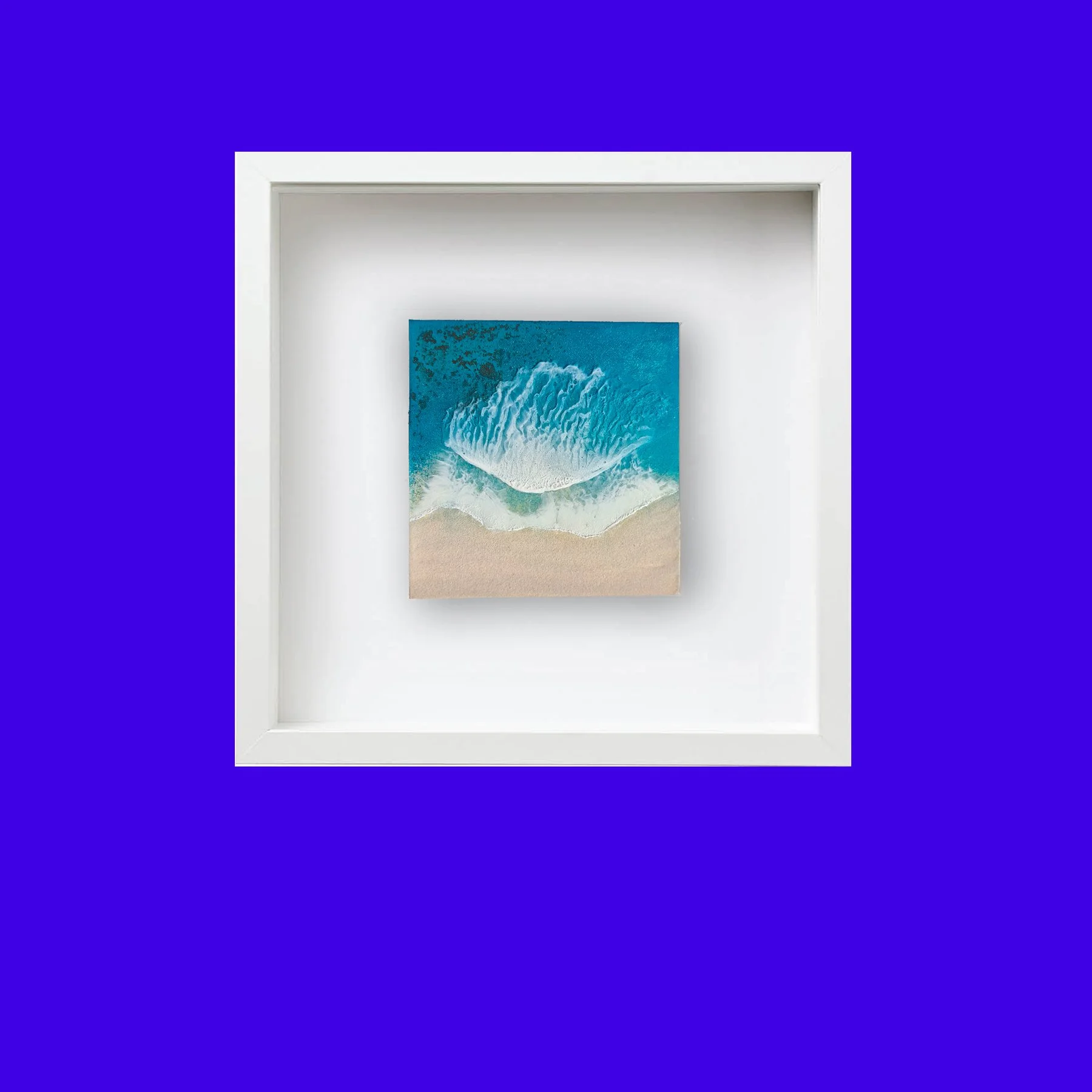 Framed square resin artwork of an ocean wave, with real sand and deep blue water details, by Irish artist Orla Doyle.