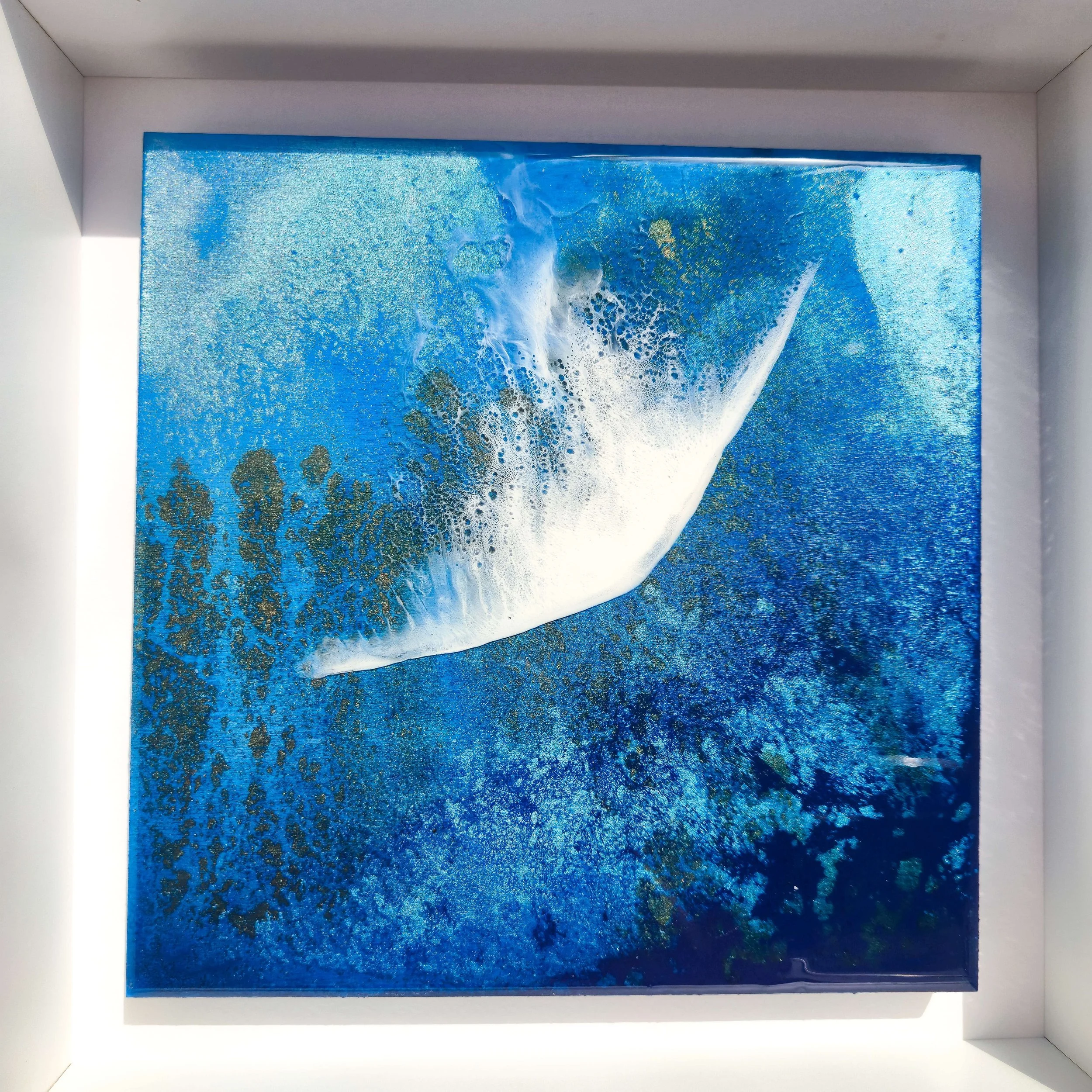 Silver Springs resin artwork hung on white wall, displaying layered blue tones and flowing white water forms with high-gloss finish.