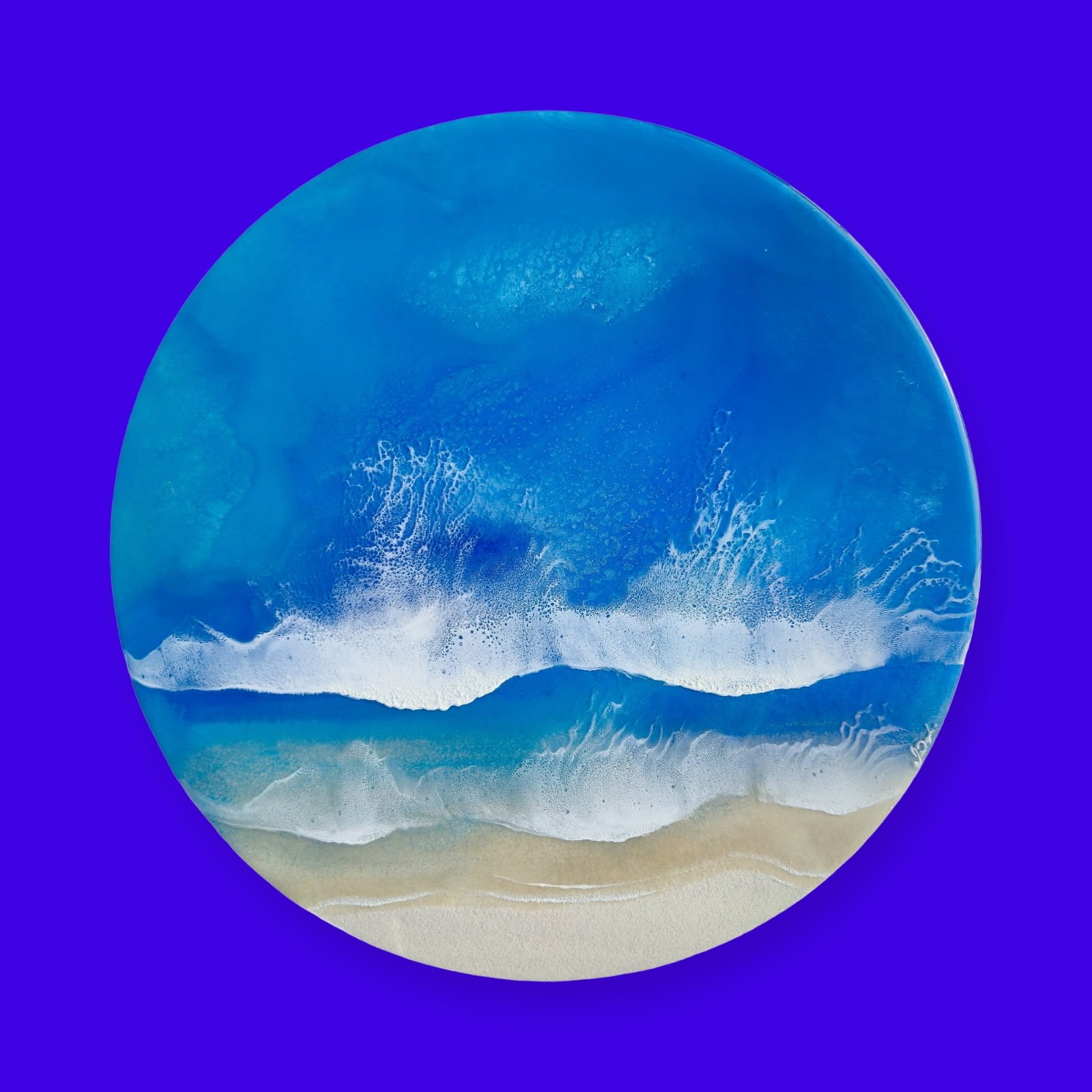 Round resin artwork featuring turquoise ocean water, two white foam wave bands, and sandy shoreline in realistic detail.