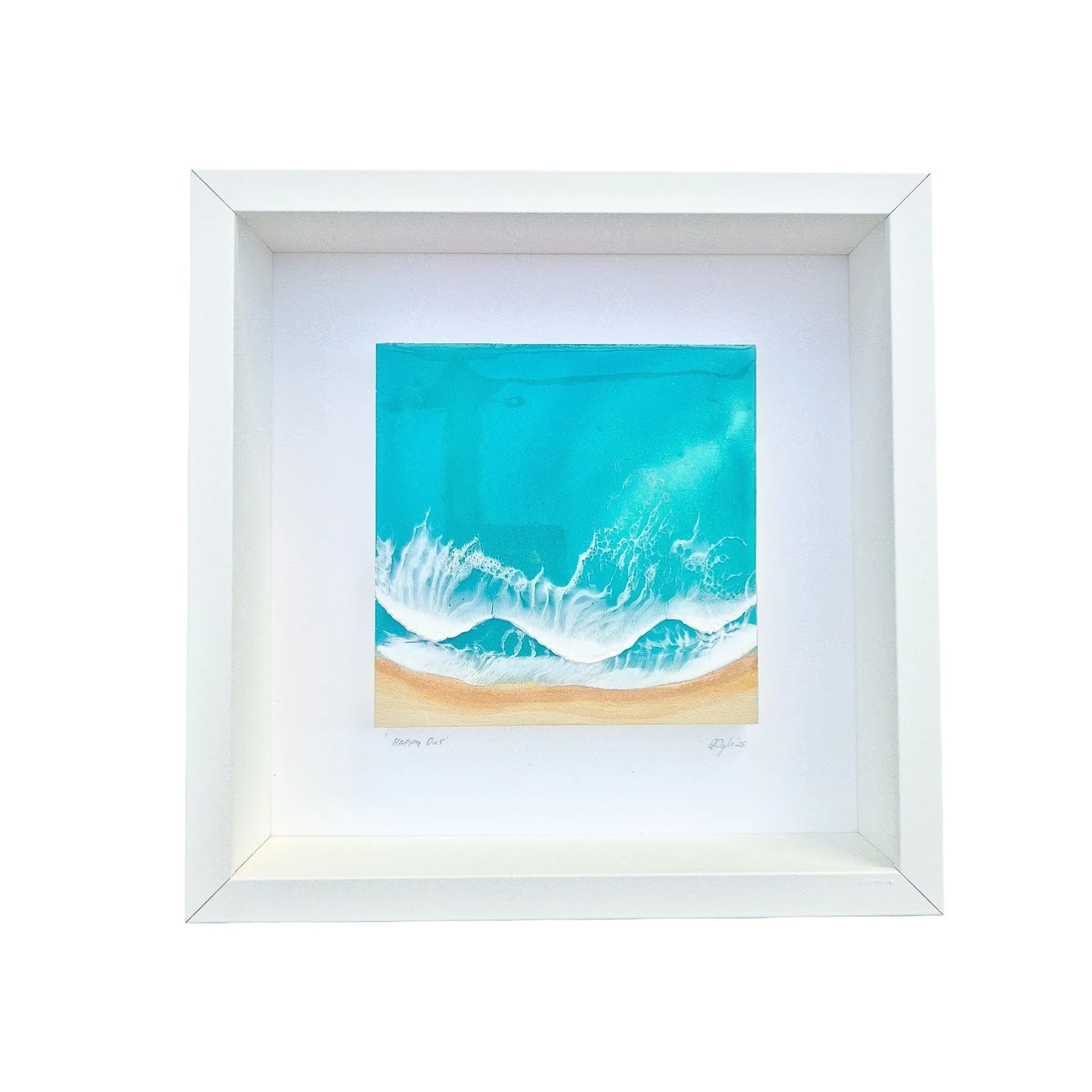 Framed resin artwork with turquoise ocean waves and sandy beach, displayed in white shadow box with glass-like finish.
