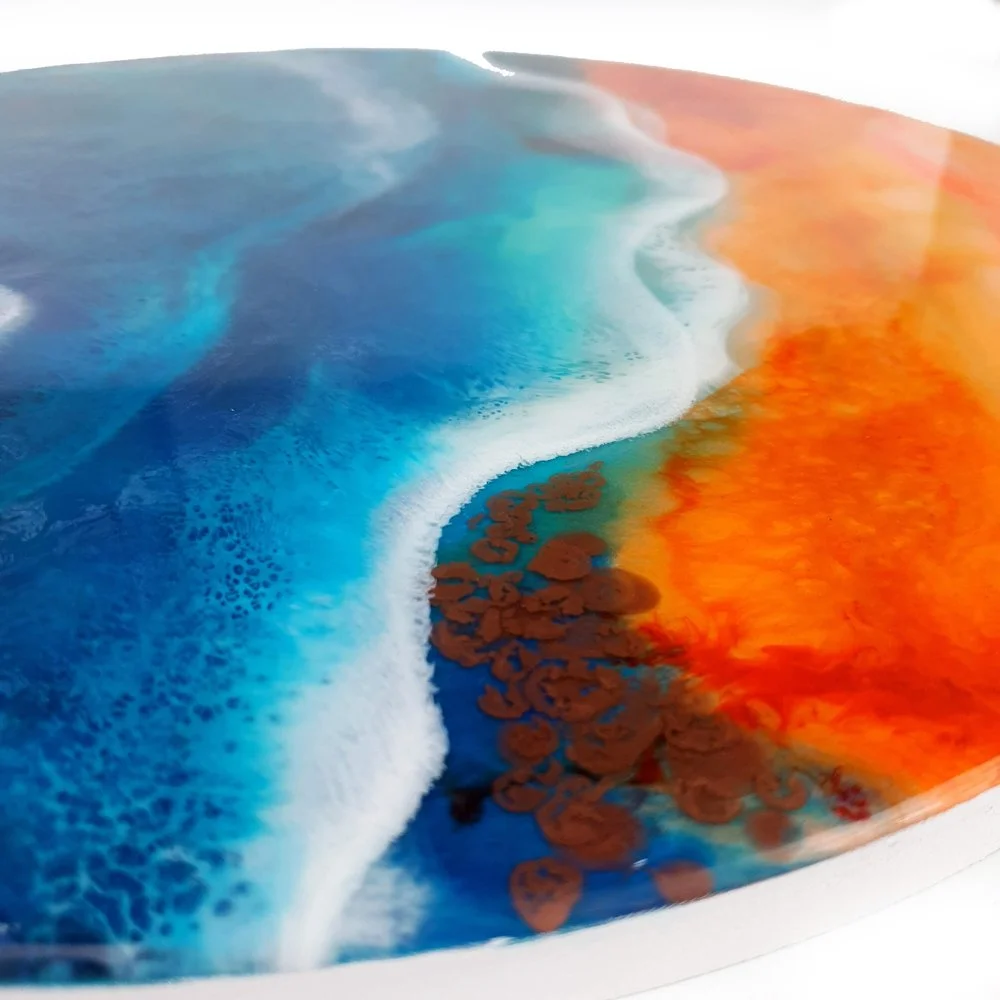 Resin artwork featuring vibrant blue and fiery orange tones, inspired by tropical coastlines, handcrafted on wood with a high-gloss finish.