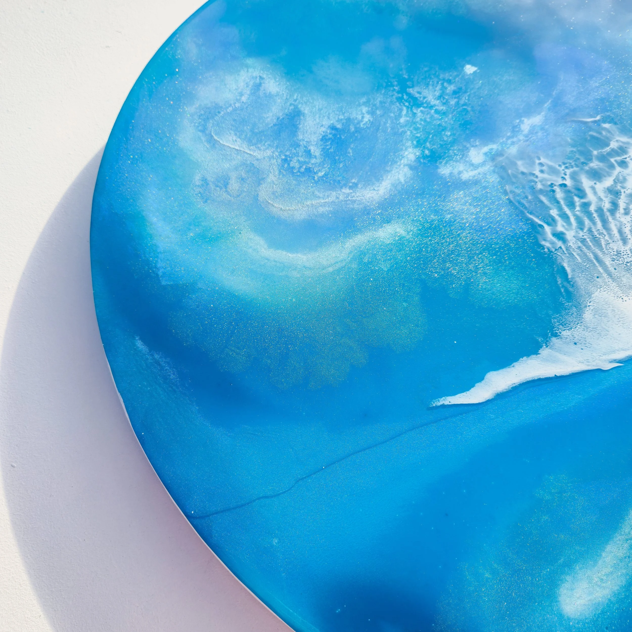Round resin artwork featuring bright turquoise ocean water with curved white foam wave and detailed spray texture.