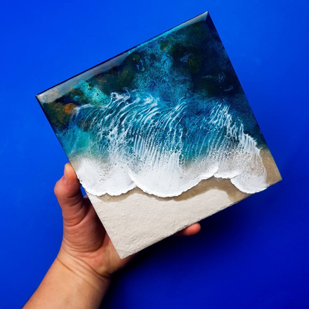 Resin artwork featuring vibrant blue ocean waves and real sand, ocean inspired.