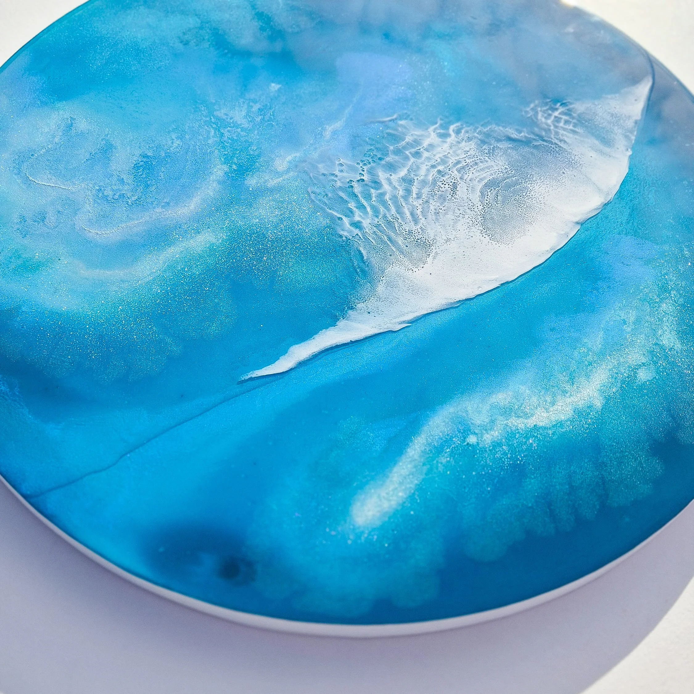 Round resin artwork featuring bright turquoise ocean water with curved white foam wave and detailed spray texture.