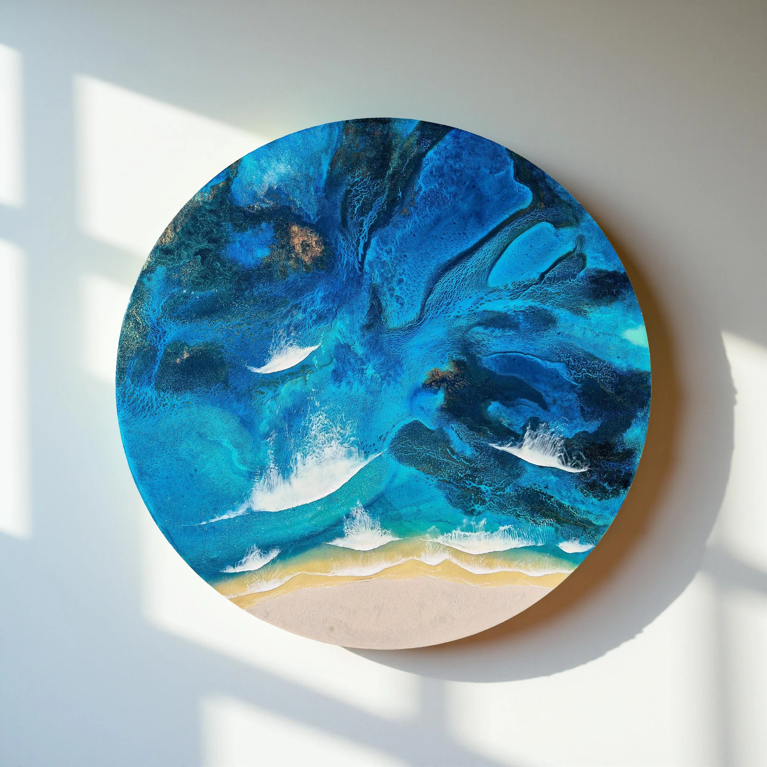 Large round resin artwork with swirling blue ocean textures and sandy shoreline, featuring a high-gloss finish on wood panel.