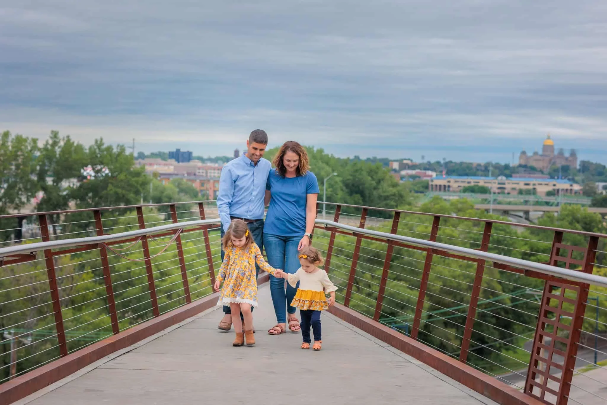 Family of 4 having fun at Macrae Park in Des Moines, with the state capitol building in the background.