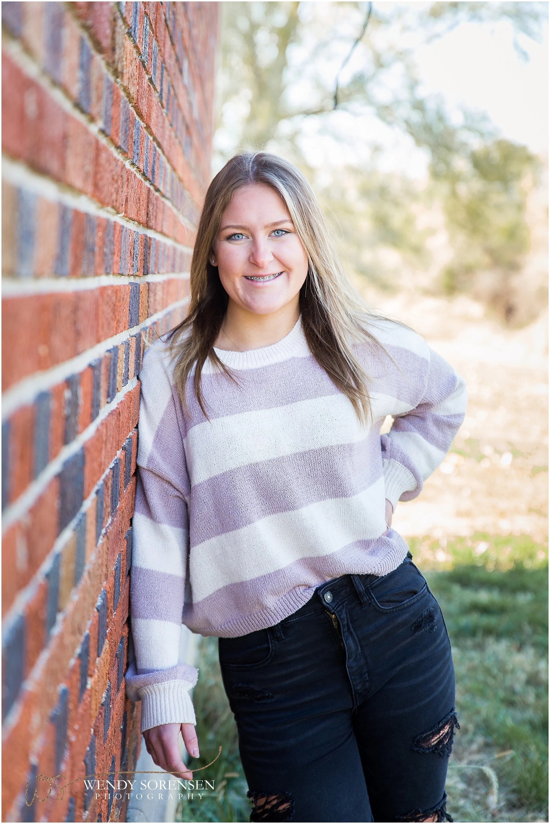 Senior girl leaning against a brick wall in Des Moines.