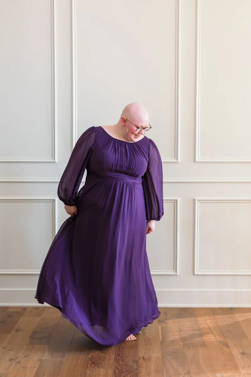 High school senior girl twirling in purple prom dress.