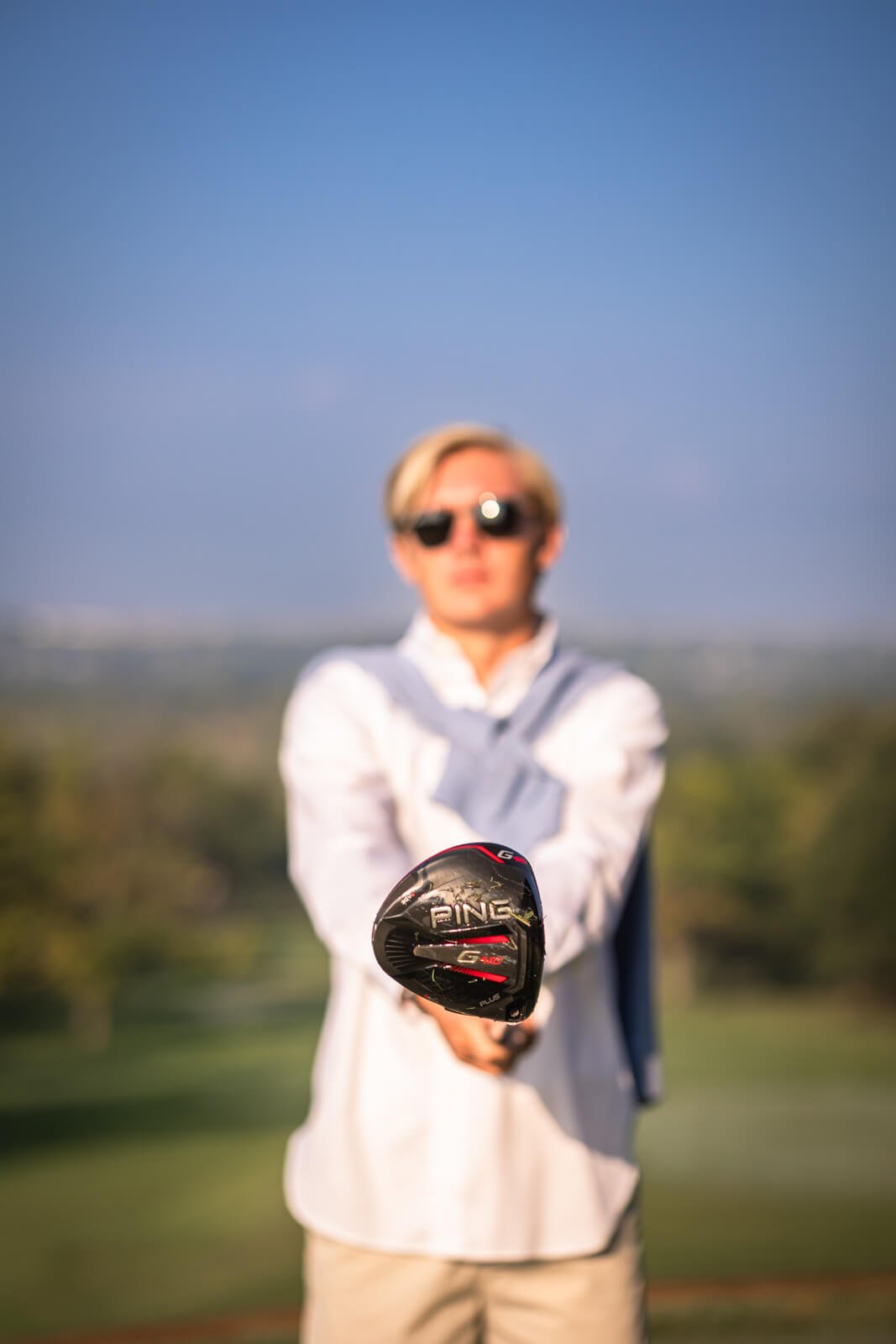 Senior boy holding golf club out in front of him, with the club in focus but the boy is blurred.