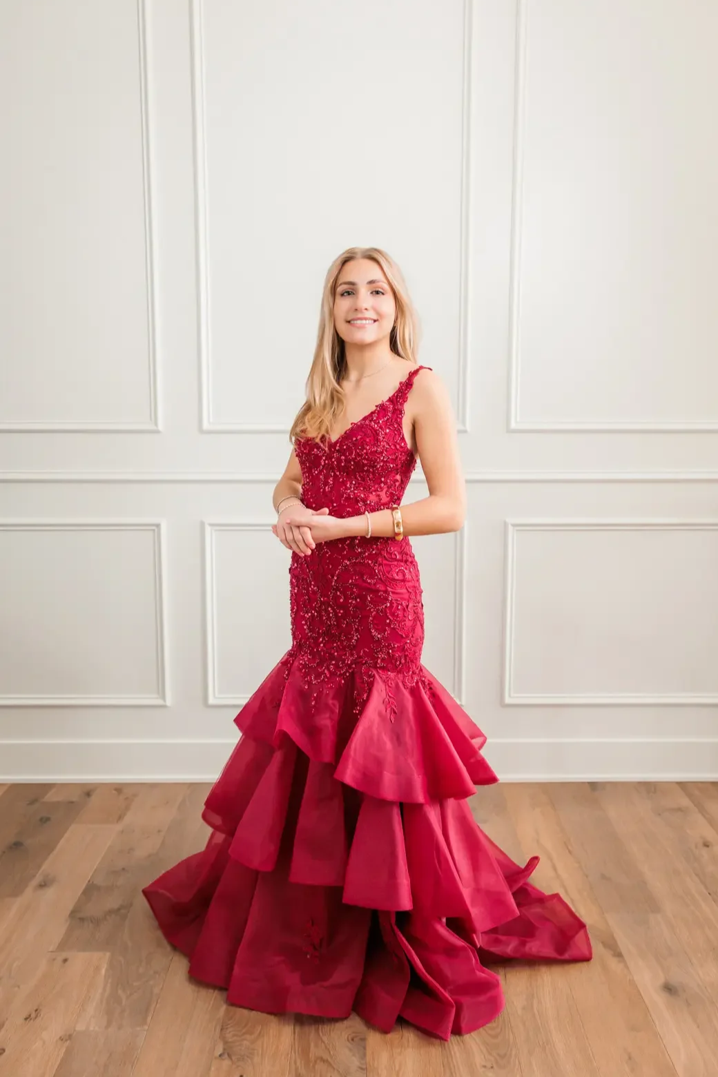 Senior girl wearing mermaid style red sequin Ellie Wilde prom dress with ruffles.