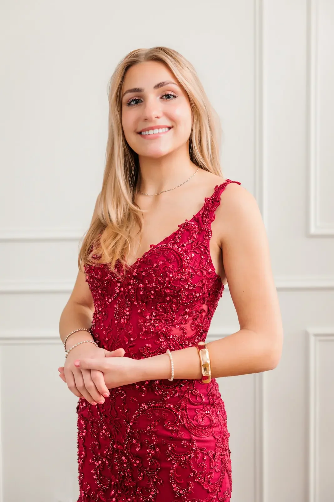 Close up of senior girl with long blonde hair wearing a red fitted, sequin prom dress in Des Moines.