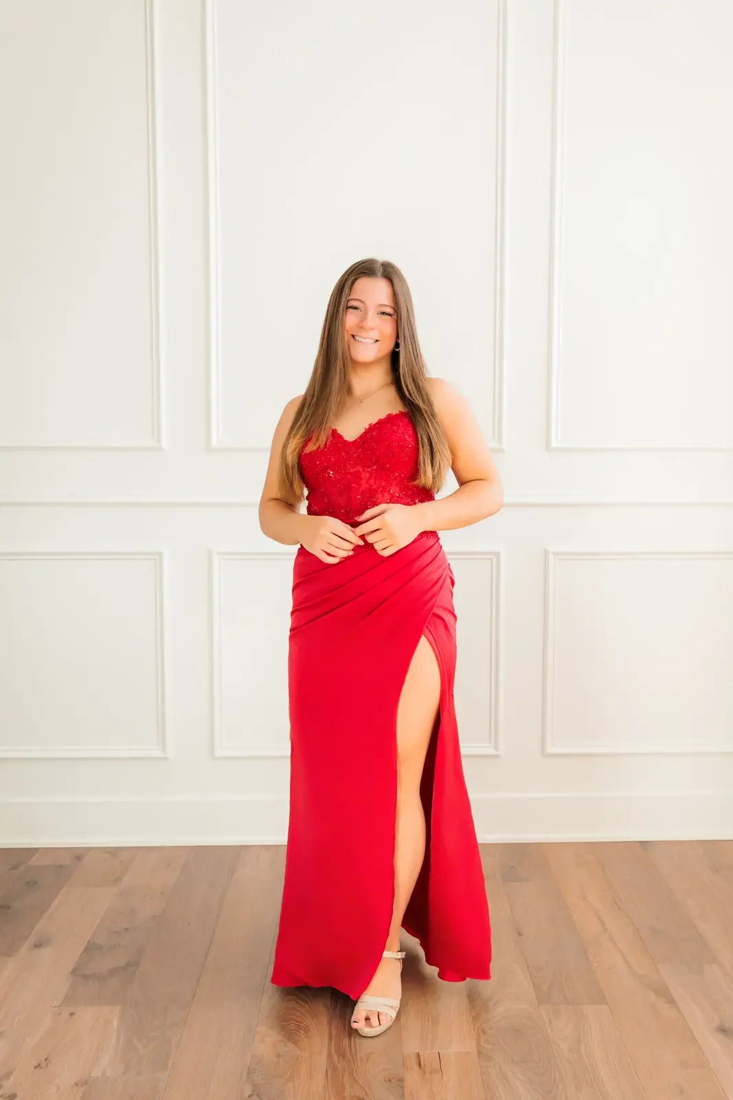 Senior girl with long brown hair wearing a floor length red prom dress.