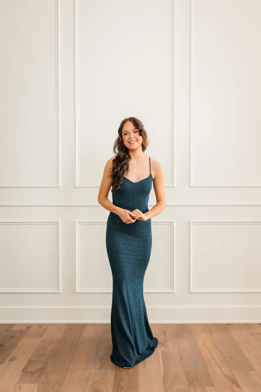 Senior girl with long brown hair wearing a dark teal prom dress.