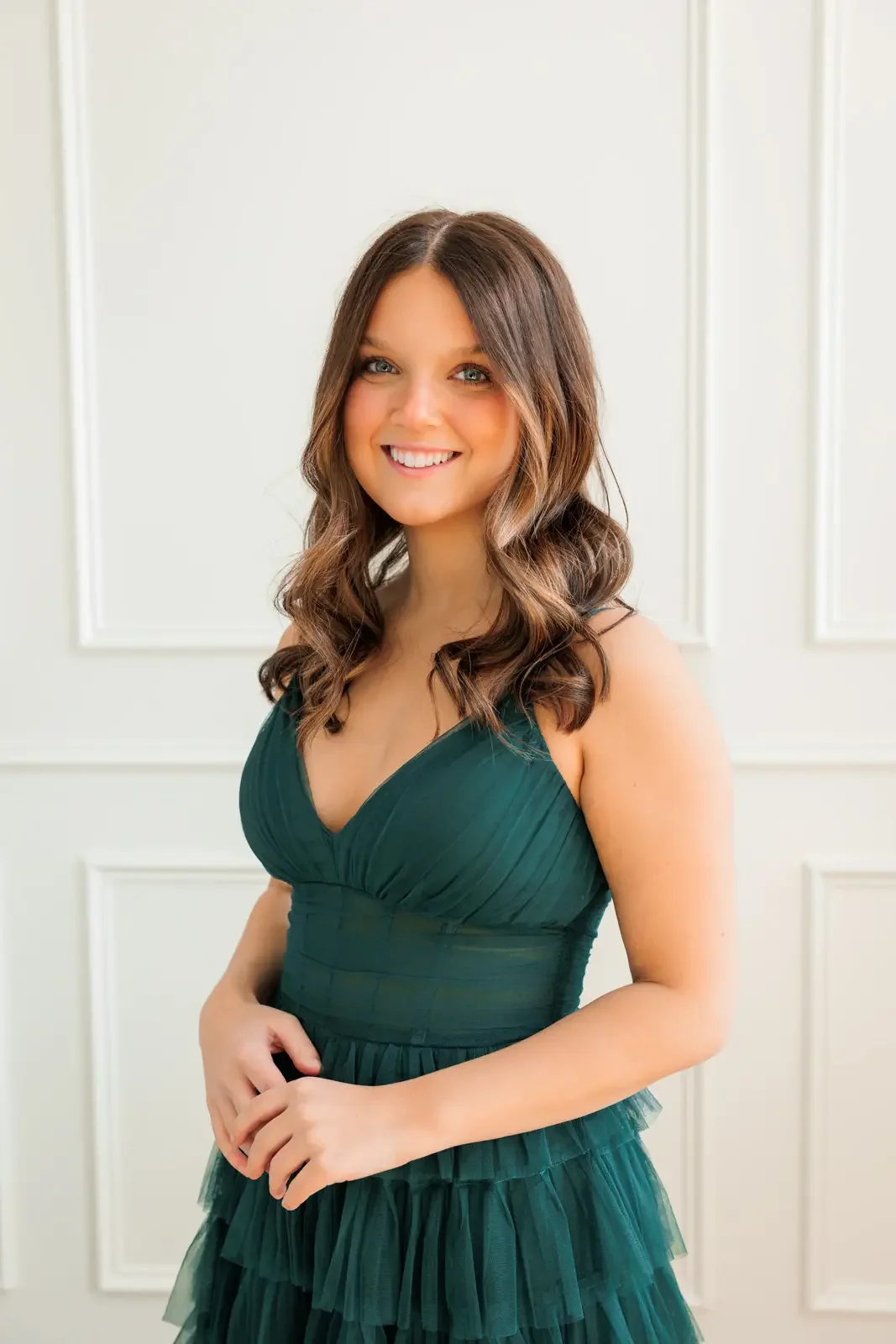 Close up of senior girl with long dark hair wearing a dark green prom dress.