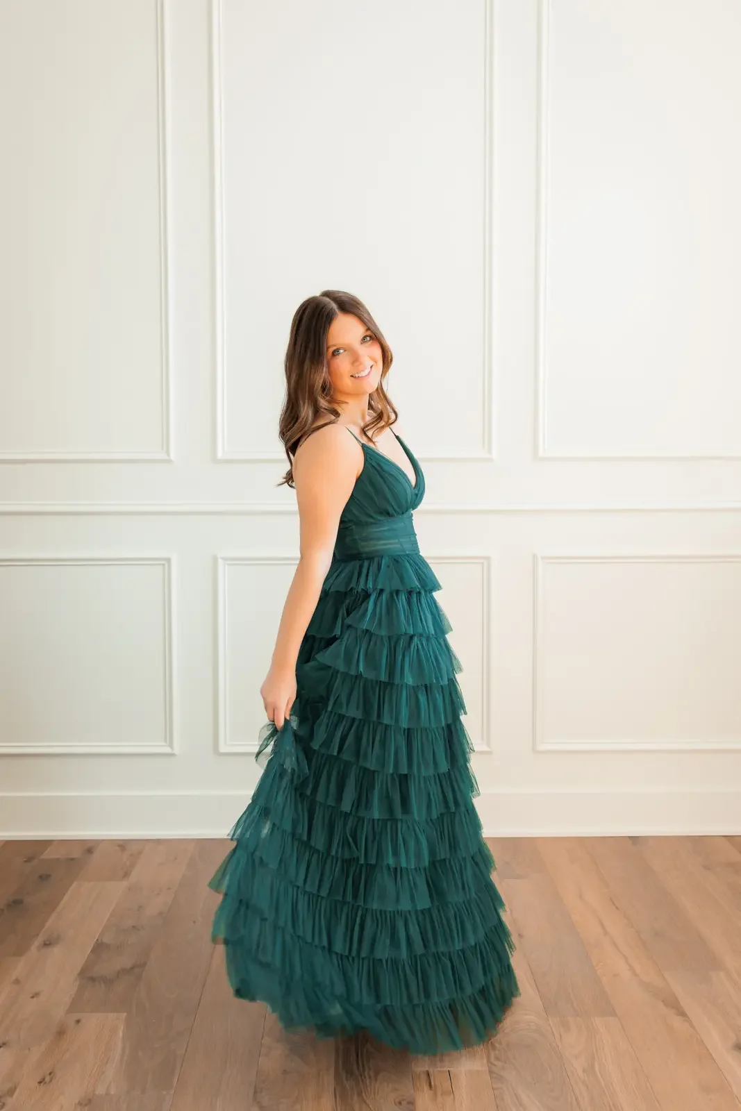 Senior girl spinning while wearing her long green prom dress.