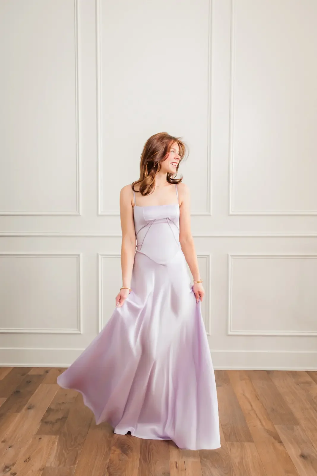 Senior girl twirling in a satin lavendar floor length prom dress.