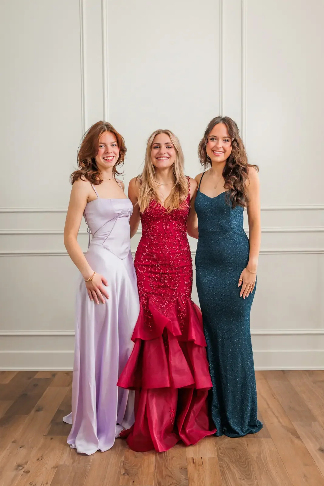 Three high school senior girls standing together in their prom dresses.