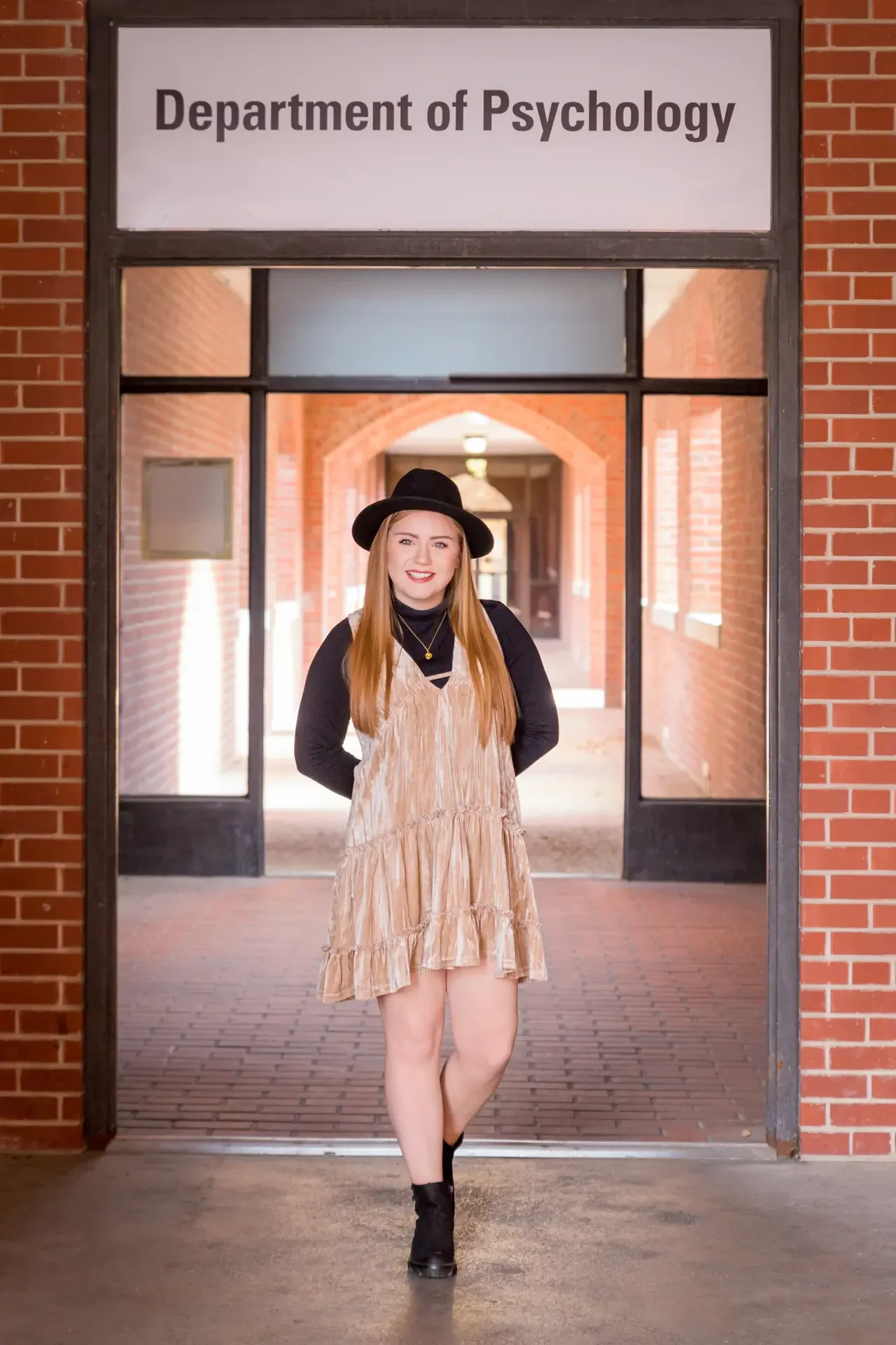 College grad standing in front of the Department of Psychology at Iowa State University in Ames.