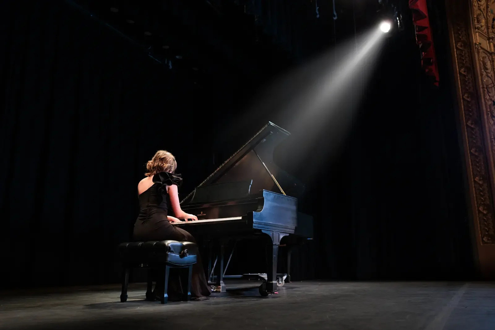 Senior girl playing a grand piano on the Hoyt Sherman Theater stage in Des Moines.