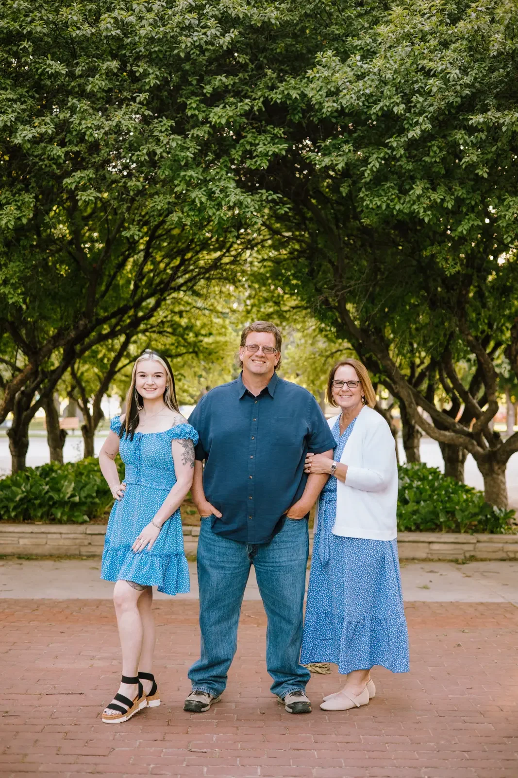 Family of 3 wearing blue standing near trees at the Iowa State Fairgrounds.