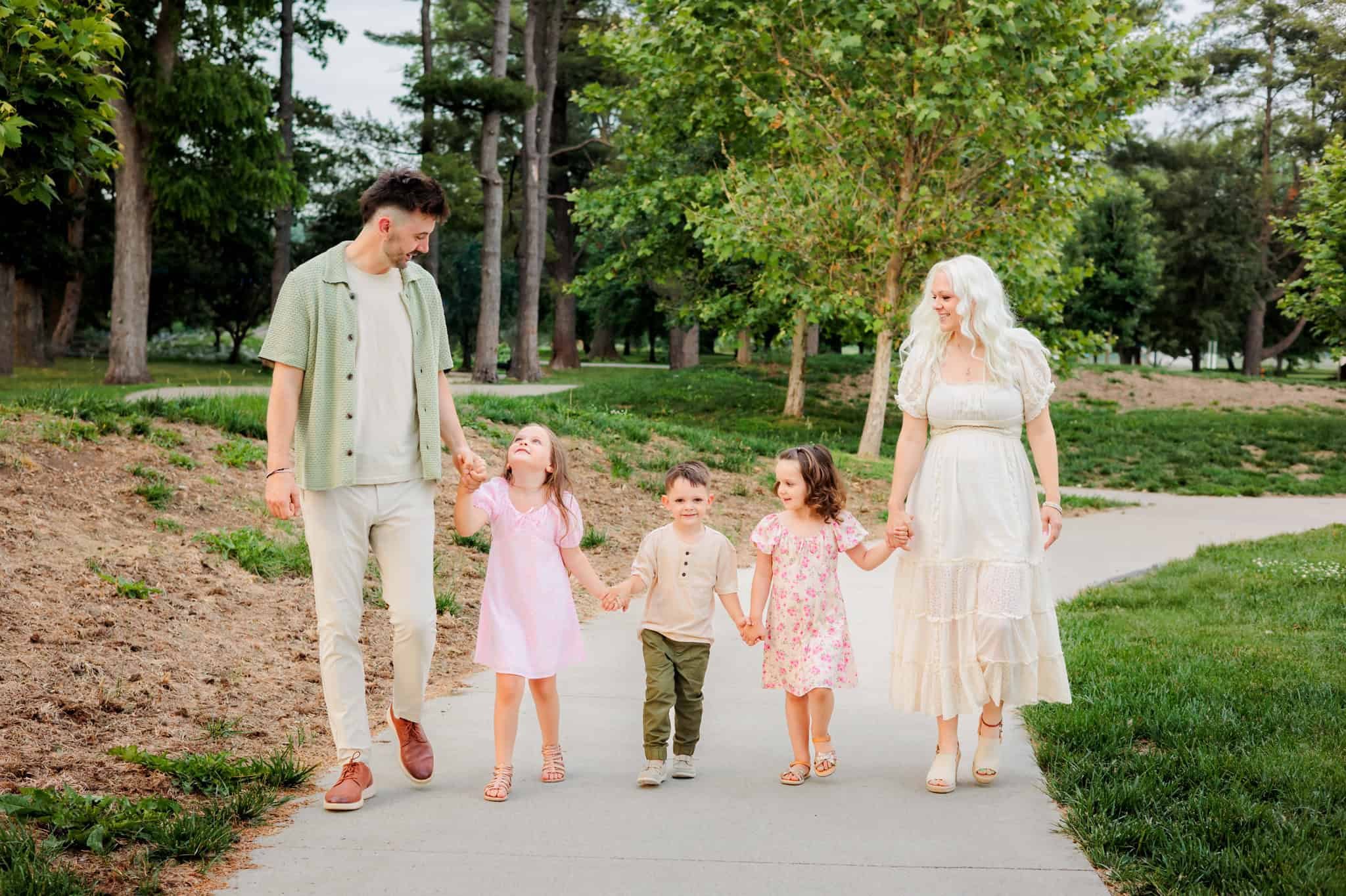 Family of 4 walking hand in hand at a Des Moines park.