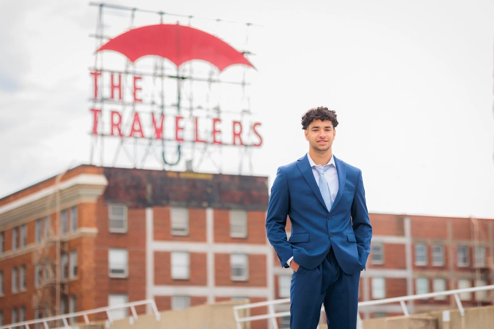 Senior guy wearing blue suit with The Travelers sign in the background.
