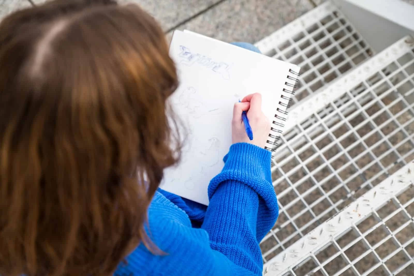 Teen girl drawing on a sketch pad at the Des Moines Art Center.