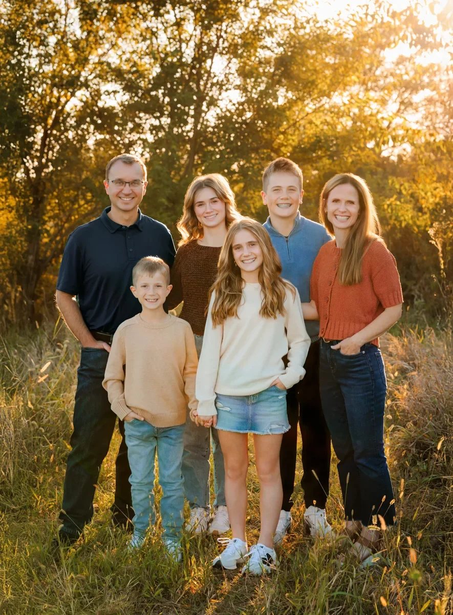 Family of 6 standing in tall autumn grasses at sunset during their portrait session.