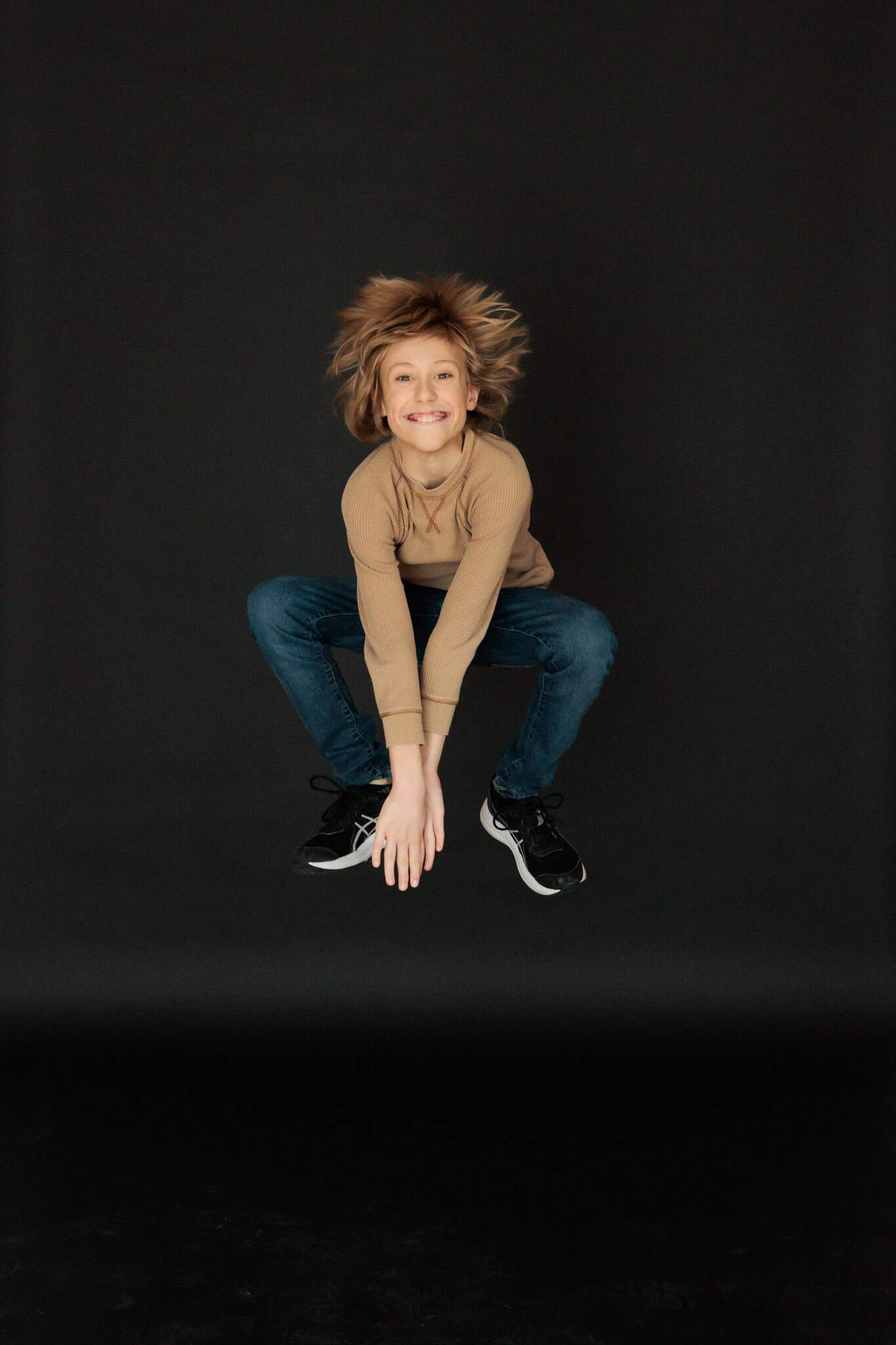 Pre-teen boy jumping with his hair flowing in the wind.