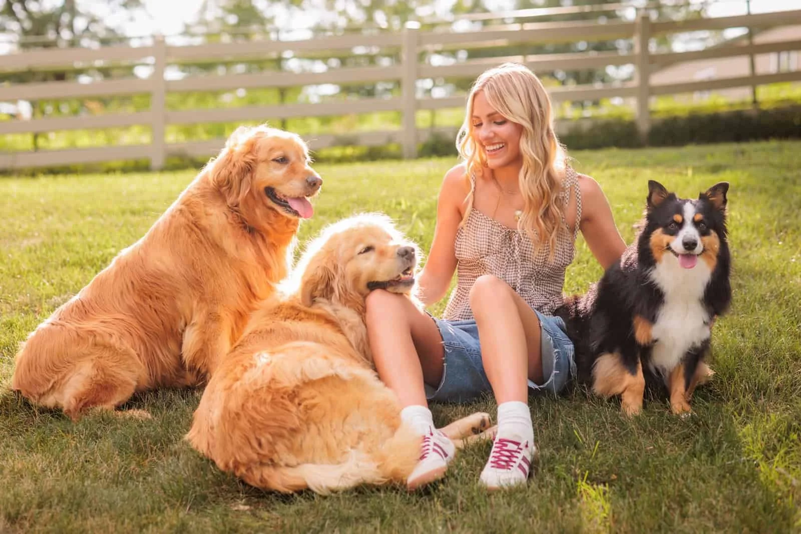 Senior girl with long blonde hair sitting in the grass with her dogs out in the country outside of Des Moines, Iowa.