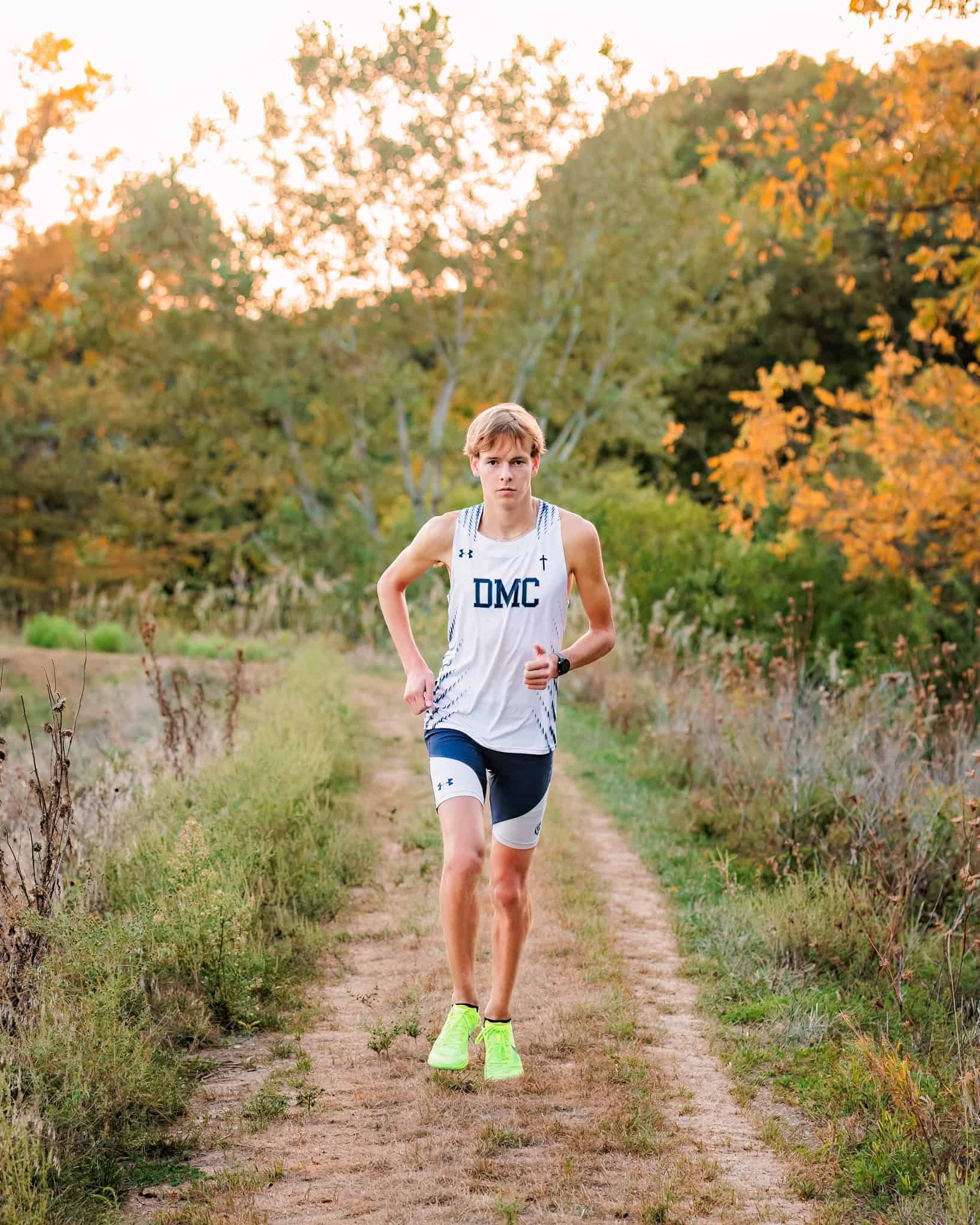 High school cross country runner running on a nature path.