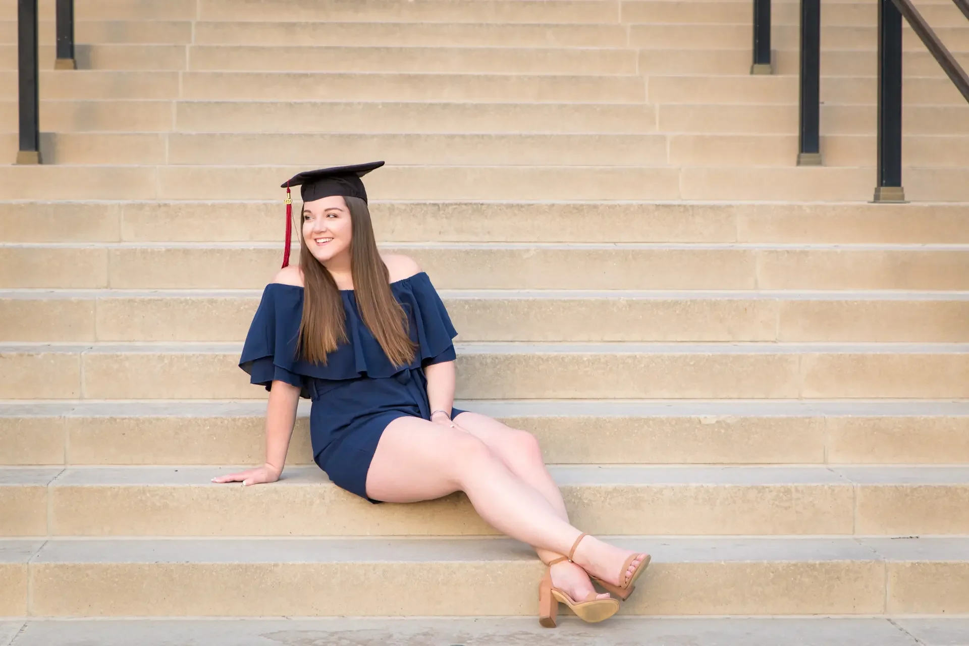 College senior girl with long brown hair sitting on the steps of Curtis Hall at Iowa State University.