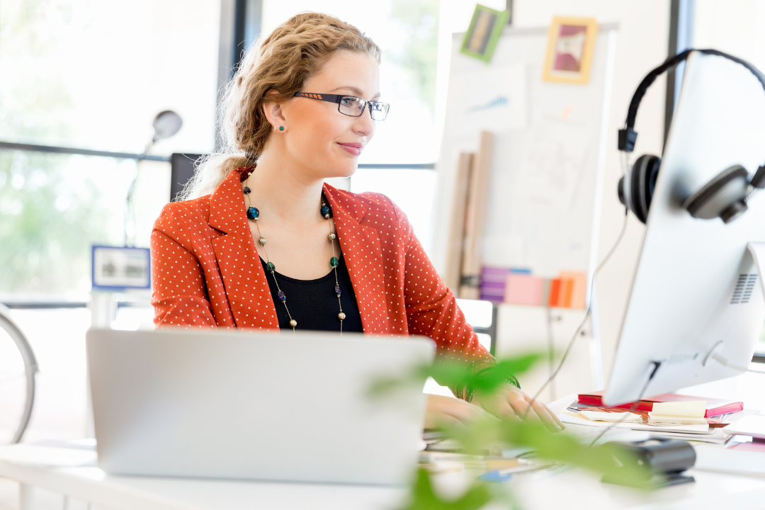 An auditor working at her desk with a computer and headset