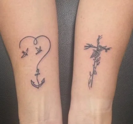 Two tattoos on inner forearms; the left tattoo is a heart-shaped fishing hook with birds flying out, and the right tattoo is a cross made of thorns with a rose wrapped around it.