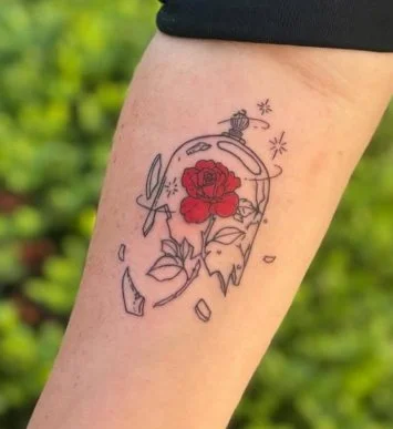 Tattoo of a broken glass with a red rose inside, some shards scattered around, and a knife crossed nearby.