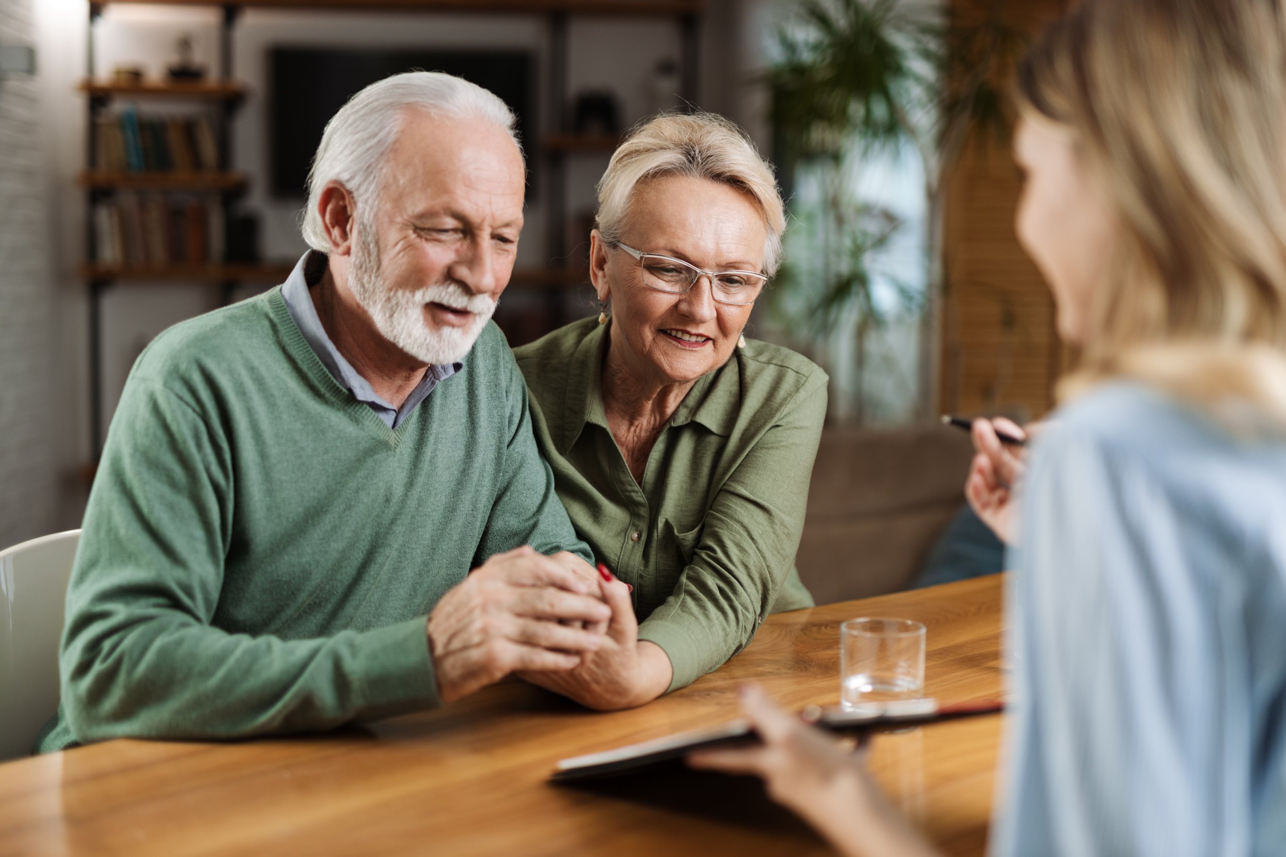 Older couple sitting at a table with a woman, talking to a therapist or counselor during a therapy session.
