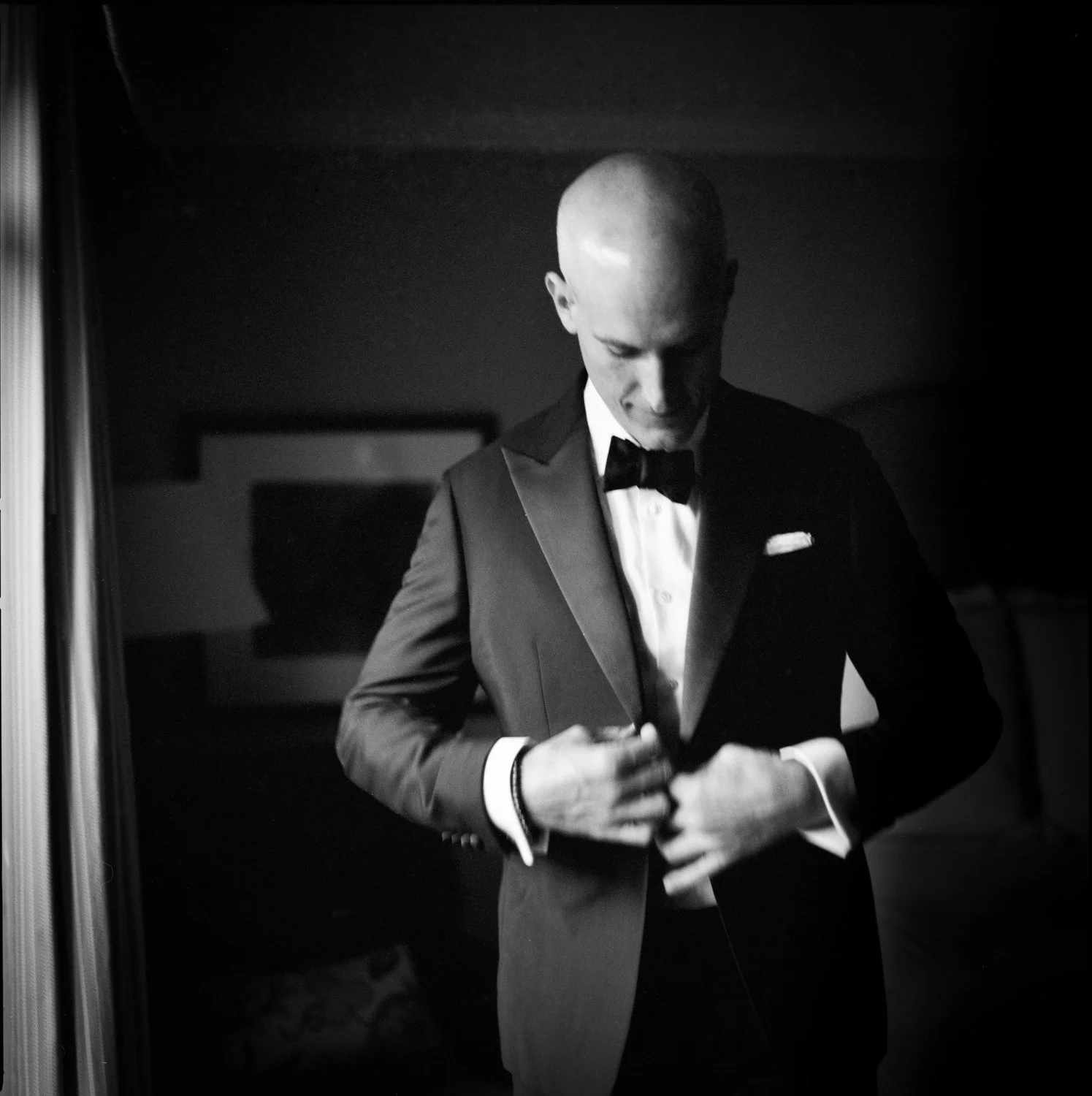 A medium format film photograph of a groom getting ready in his hotel room. The photograph has slight motion blur and a soft look. By Christina Richards a Boston based photographer.