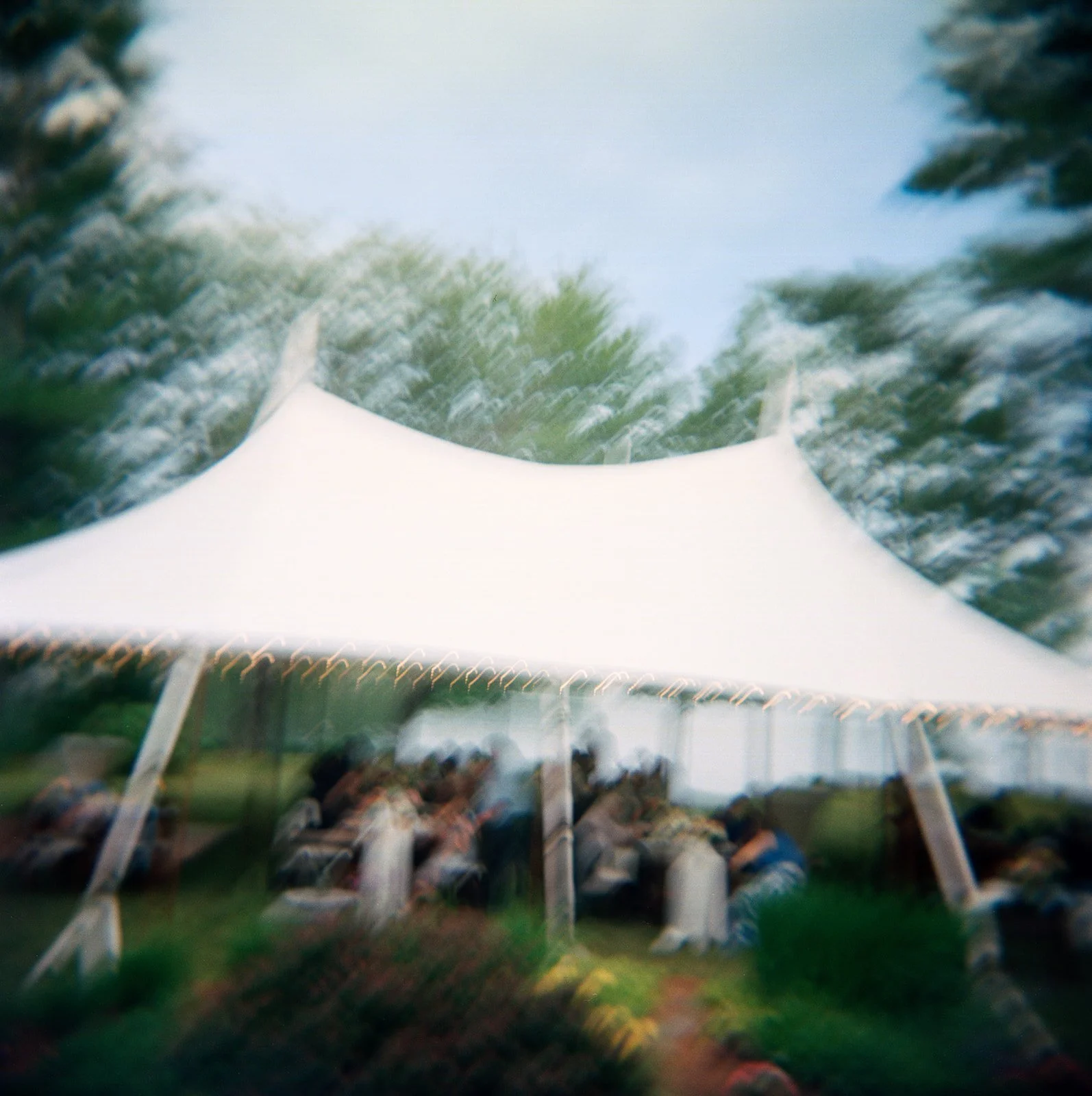 A blurry color film photograph of a tented wedding in a Maine backyard. The photo is by Boston based wedding photographer Christina Richards.