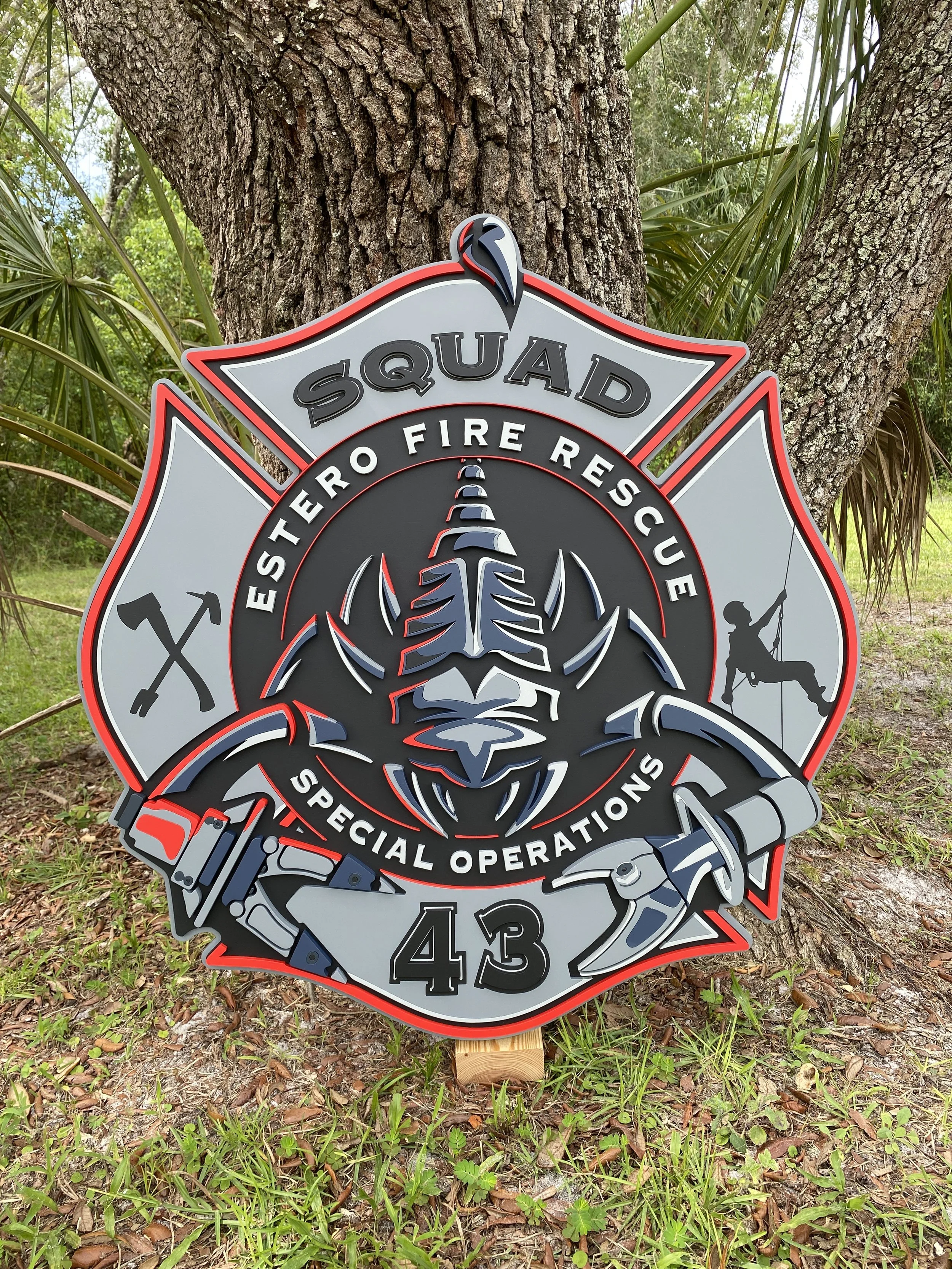 3D Wall Art Estero Fire Rescue's Squad 43, depicting a scorpion, firefighter tools, a firefighter working on a harness, an axe, and a halligan.