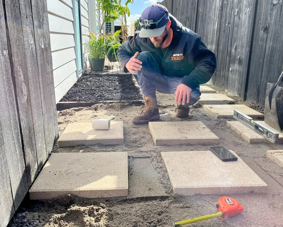 A man installing square pavers.