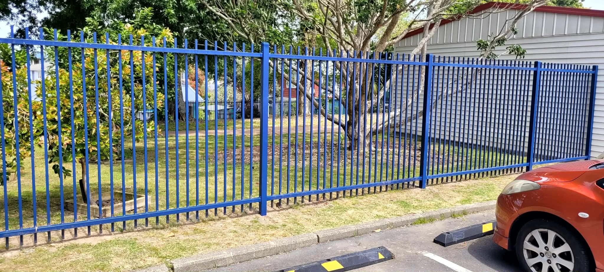 Blue steel boundary fencing to secure a school property.