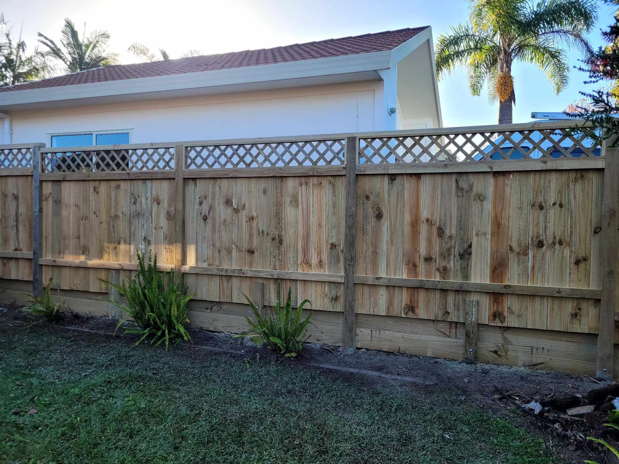 New retaining wall with a boundary fence and trellis installed on top.